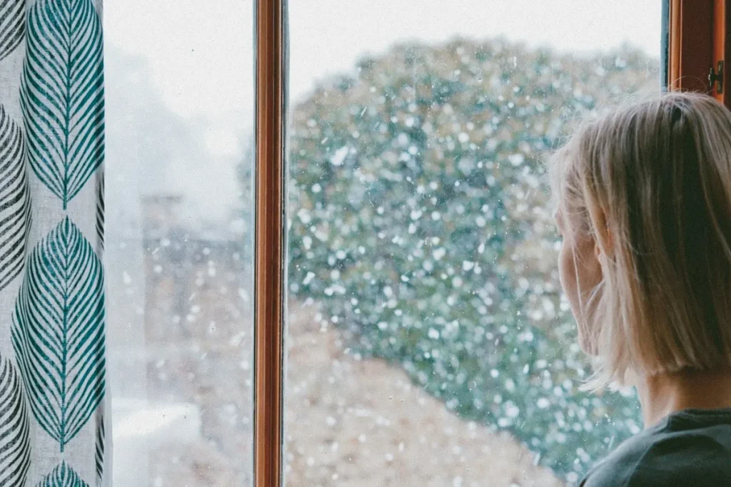 Mujer mirando por una ventana en un día lluvioso
