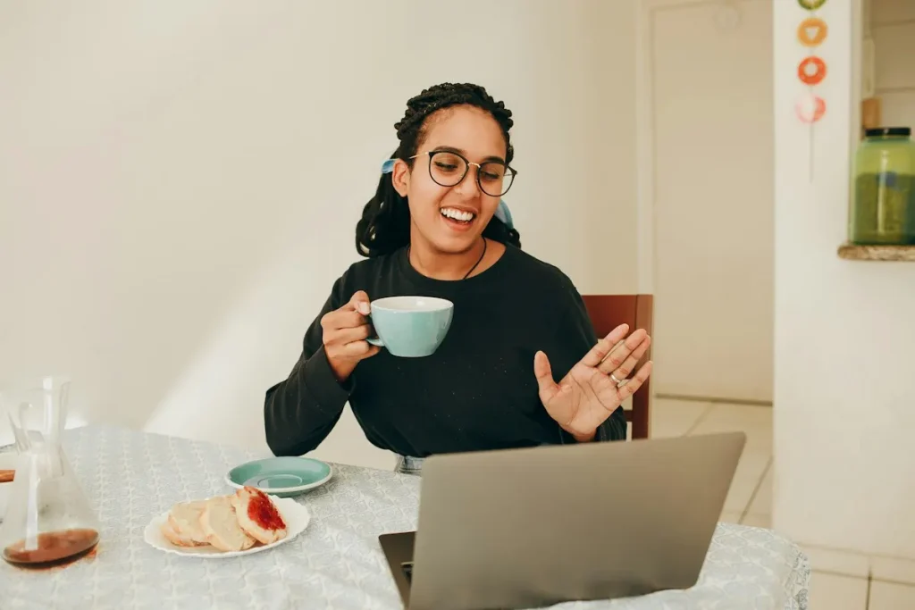 Mujer sonriente con una taza en una videollamada desde su casa